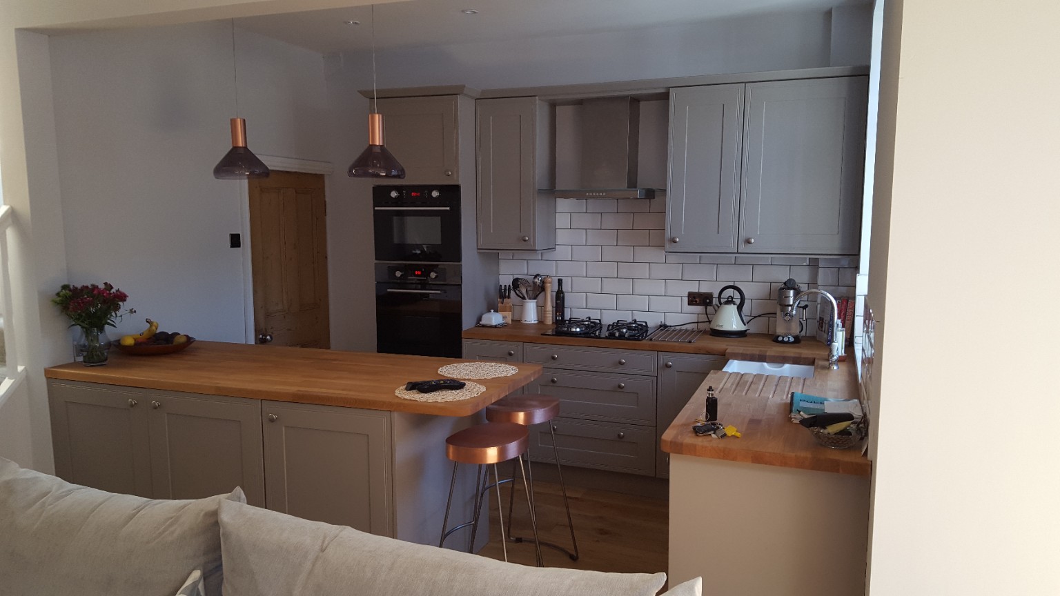 Grey cabinetry, timber worktops and a breakfast peninsula. Fitted by RCB.